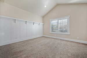 Carpeted spare room with lofted ceiling