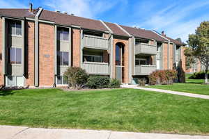 View of front of property featuring a balcony and a front lawn