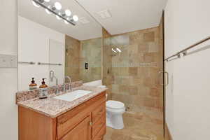 Bathroom with toilet, vanity, and a walk-in shower with door