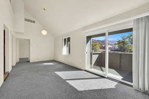 Empty room featuring a mountain view, carpet floors, and high vaulted ceiling