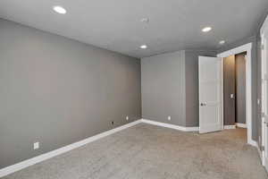 Empty room featuring light carpet and a textured ceiling