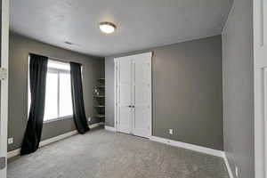 Unfurnished bedroom with light carpet and a textured ceiling