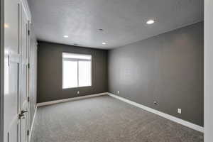 Empty room featuring a textured ceiling and carpet