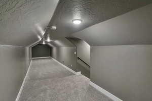 Bonus room featuring lofted ceiling, carpet, and a textured ceiling