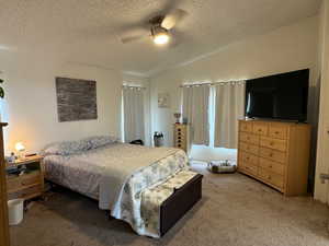 Carpeted bedroom with ceiling fan, a textured ceiling, and vaulted ceiling