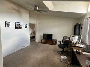 Home office featuring vaulted ceiling, ceiling fan, a textured ceiling, and carpet flooring