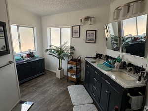 Bathroom featuring vanity, vaulted ceiling, a textured ceiling, and wood-type flooring