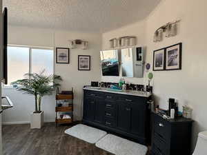 Bathroom featuring a textured ceiling, hardwood / wood-style flooring, toilet, vanity, and crown molding