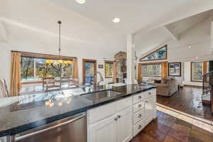 Kitchen with a stone fireplace, white cabinetry, a healthy amount of sunlight, and sink