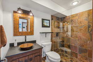 Bathroom featuring vanity, tiled shower, and toilet