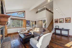 Living room featuring beam ceiling, a fireplace, high vaulted ceiling, and dark hardwood / wood-style flooring