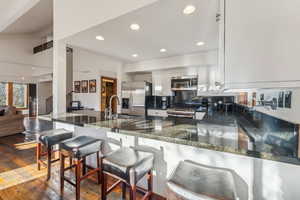 Kitchen featuring tasteful backsplash, appliances with stainless steel finishes, sink, white cabinets, and dark wood-type flooring