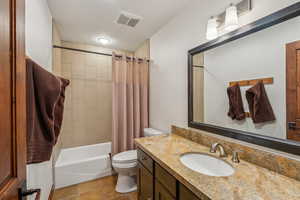 Full bathroom with shower / bath combination with curtain, toilet, tile patterned flooring, and vanity