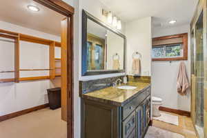 Bathroom with vanity, toilet, a shower with shower door, and tile patterned flooring