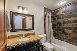 Full bathroom featuring toilet, vanity, and shower / bath combination with curtain