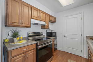 Kitchen with stainless steel electric range and light hardwood / wood-style flooring