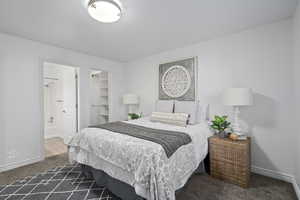 Bedroom featuring dark carpet, a walk in closet, a closet, and ensuite bath