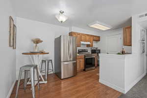 Kitchen with a breakfast bar, stainless steel appliances, and light hardwood / wood-style floors