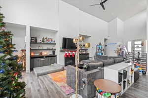 Living room featuring ceiling fan, a high ceiling, and hardwood / wood-style flooring