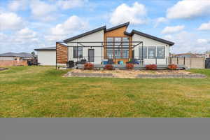 Back of property with glass enclosure and a yard