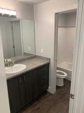 Full bathroom featuring wood-type flooring, shower / bathing tub combination, a textured ceiling, toilet, and vanity