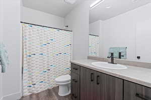 Bathroom with hardwood / wood-style flooring, vanity, toilet, and walk in shower