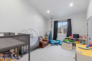 Bedroom featuring carpet flooring, a crib, and lofted ceiling