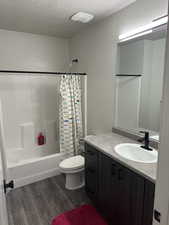 Full bathroom with vanity, shower / bath combo, hardwood / wood-style flooring, and toilet