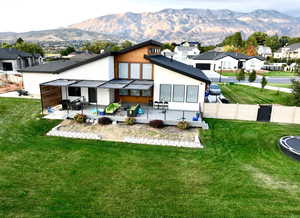 Rear view of property featuring a patio, a mountain view, and a yard