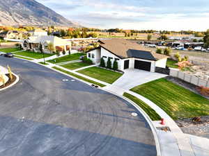 View of front of house with a garage, a mountain view, and a front lawn