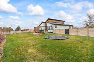 Rear view of house featuring a trampoline and a lawn