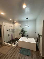 Bathroom featuring independent shower and bath, hardwood / wood-style floors, and a textured ceiling