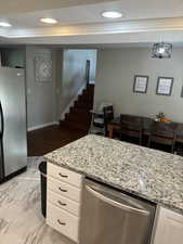 Kitchen featuring LVP flooring, stainless steel appliances, pendant lighting, white cabinets, and light granite counters