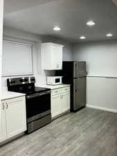 Kitchen with light LVP floors, appliances with stainless steel finishes, and white cabinets