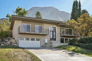 View of front of house with a mountain view, a front yard, a garage, and a balcony