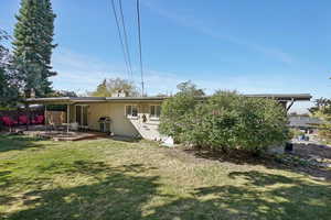 Rear view of house featuring a patio area, a deck, and a lawn