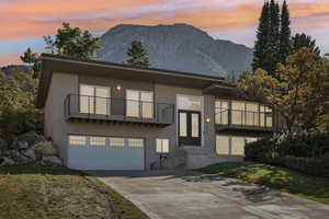 View of front of home with a balcony, a garage, and a mountain view