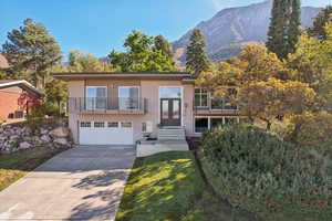 View of front facade featuring a garage, central air condition unit, a mountain view, a balcony, and a front yard