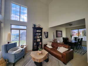 Carpeted living room with a towering ceiling and a wealth of natural light