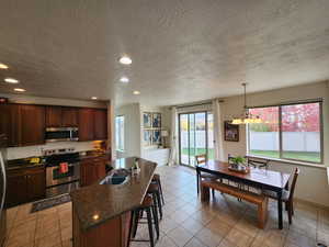 Kitchen featuring a textured ceiling, a kitchen island with sink, sink, and appliances with stainless steel finishes