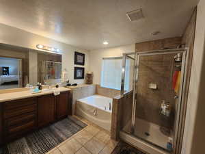 Bathroom with plus walk in shower, tile patterned flooring, vanity, and a textured ceiling