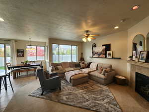 Living room with a tile fireplace, ceiling fan, light tile patterned floors, and a healthy amount of sunlight