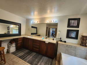 Bathroom featuring tile patterned floors, vanity, a bath, and a textured ceiling