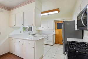 Kitchen with cabinetry, light travertine tile patterned floors, sink, and kitchen peninsula