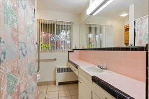 Bathroom featuring decorative backsplash, toilet, tile patterned flooring, radiator, and vanity