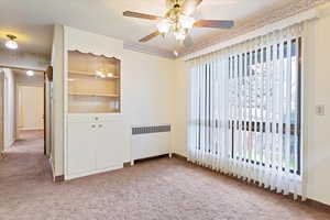 Dining room with carpet, ceiling fan, radiator heating unit, and plenty of natural light