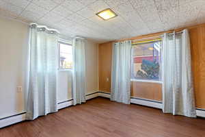 Spare room featuring a baseboard radiator and wood-type flooring