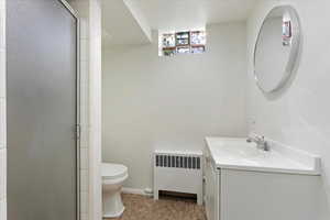 Bathroom with vanity, radiator, and a shower with door