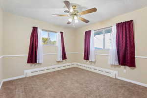 Carpeted bedroom with a baseboard radiator and ceiling fan