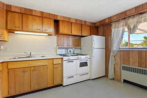 Second Kitchen with radiator heating unit, sink, and white appliances